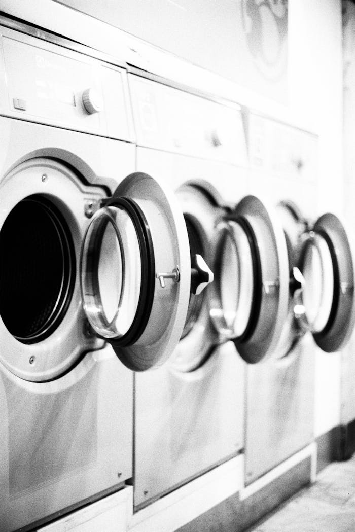 Monochrome image of open washing machines in a Lisbon laundromat.