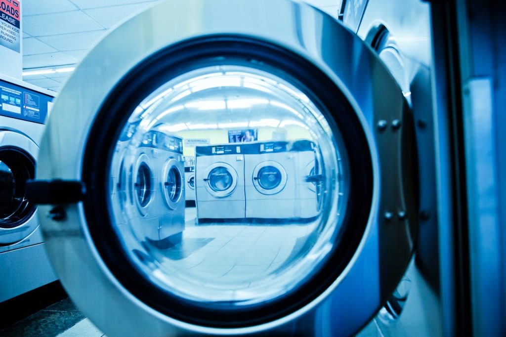 Home Interior view of a modern laundromat with rows of steel washing machines.